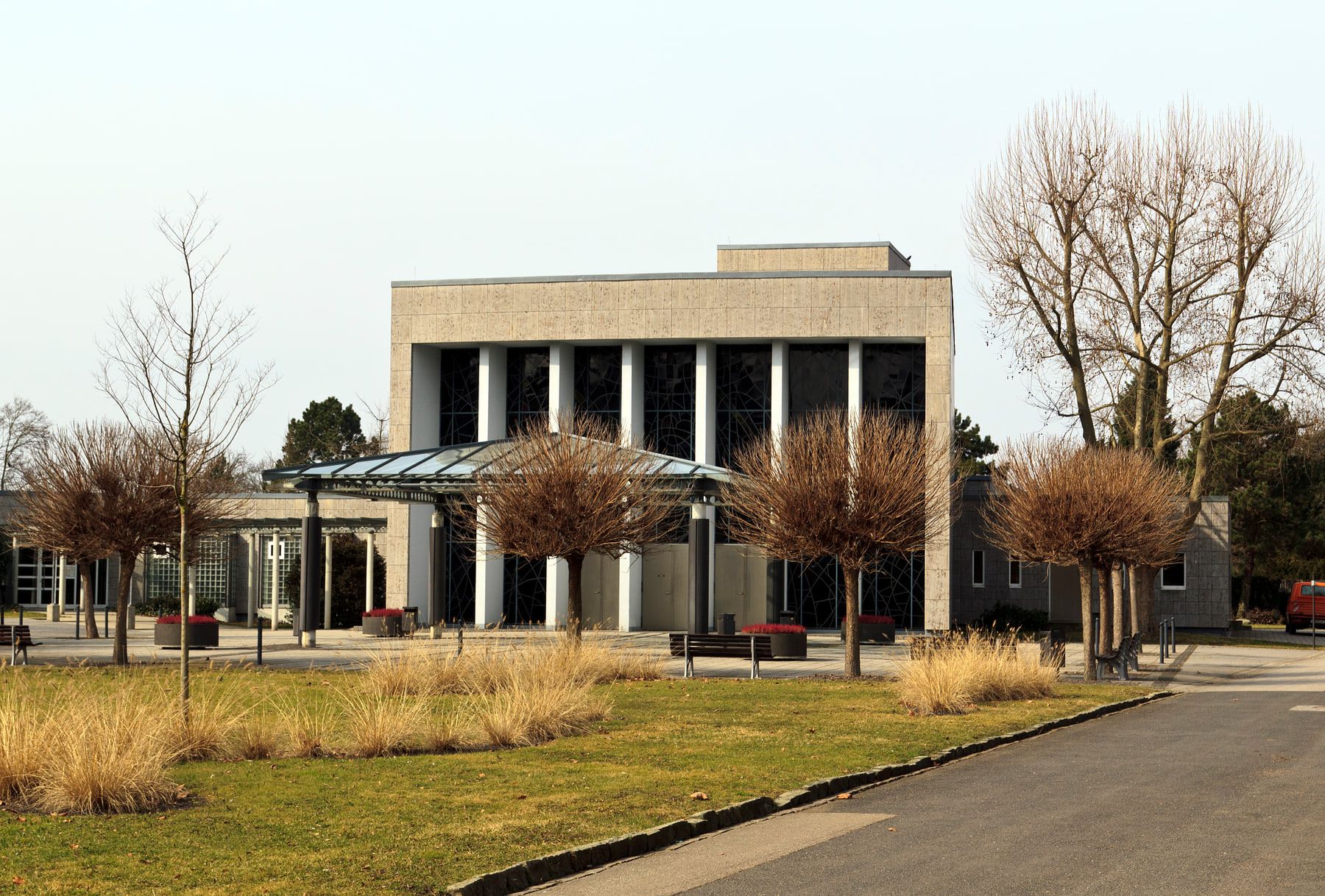Trauerhalle mit hohem Säulengeschoss und baumbestandenem Vorplatz auf Hauptfriedhof Ludwigshafen